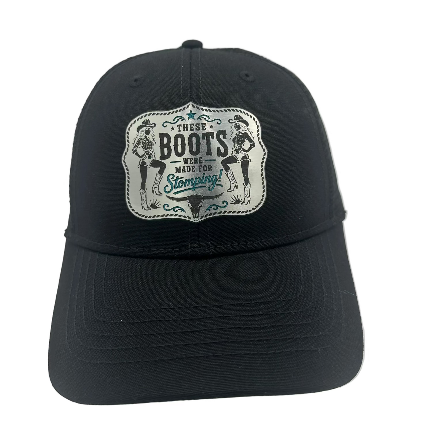 A black baseball cap with a rectangular embroidered patch on the front that reads 'These Boots Made For Stampeding West' with illustrated figures and decorative blue accents.