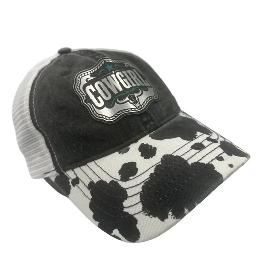 Cowgirl turquoise acrylic patch ponytail hat with cow print brim on a distressed black western cap.